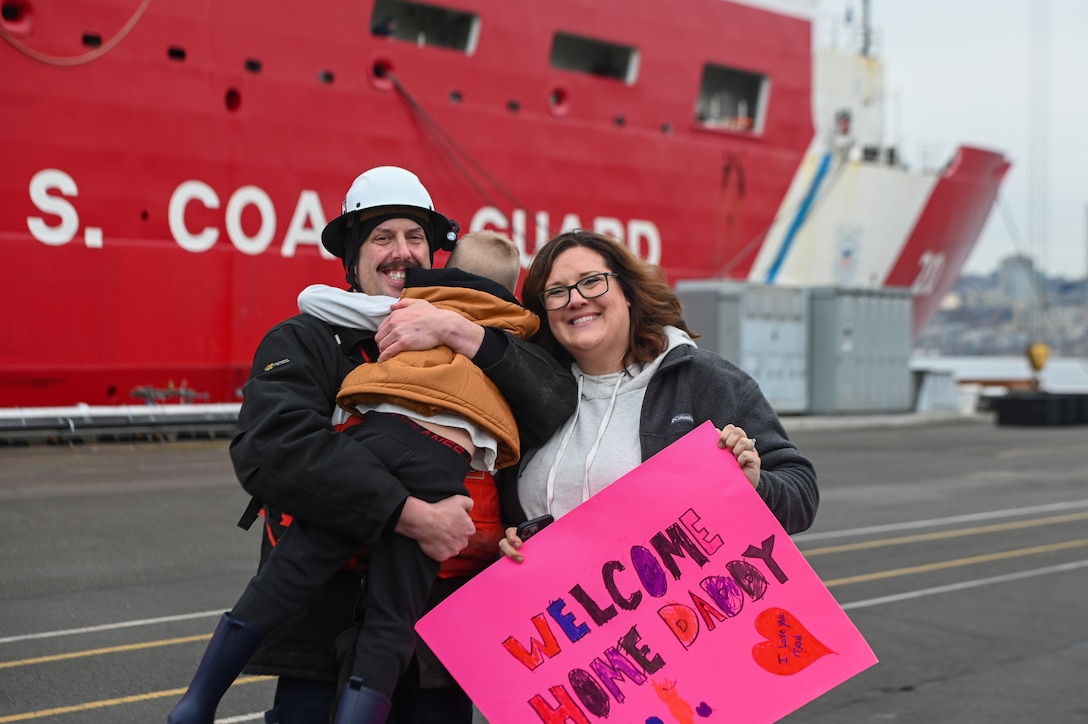 A member of the Coast Guard Cutter Healy (WAGB 20) embraces his family member on the pier at Base Seattle after a multi-month deployment, Dec. 12, 2024. The Healy is one of two icebreakers stationed in Seattle and is the only military ship dedicated to conducting research in the Arctic. (U.S. Coast Guard photo by Petty Officer 3rd Class Annika Hirschler)