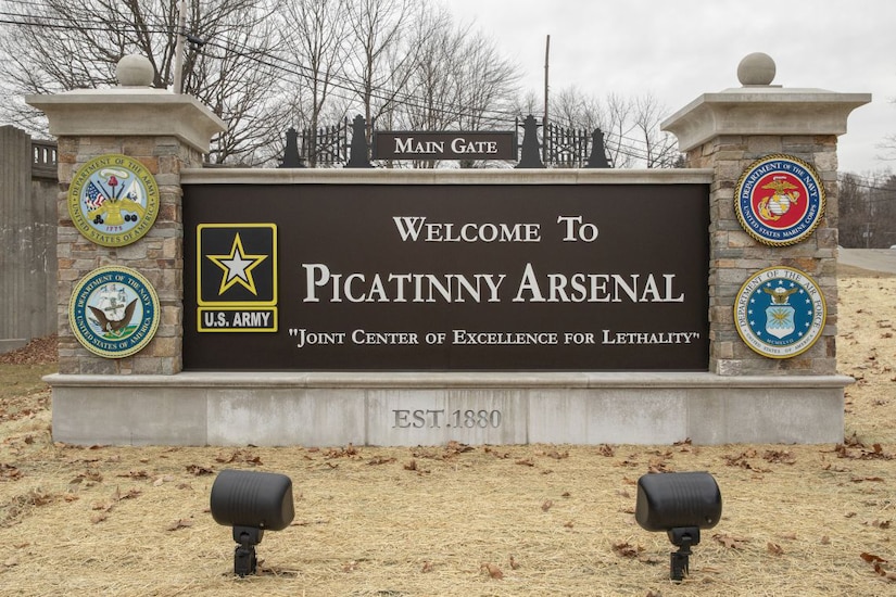 A large sign, with stone columns on each side, reads "Welcome to Picatinny Arsenal."