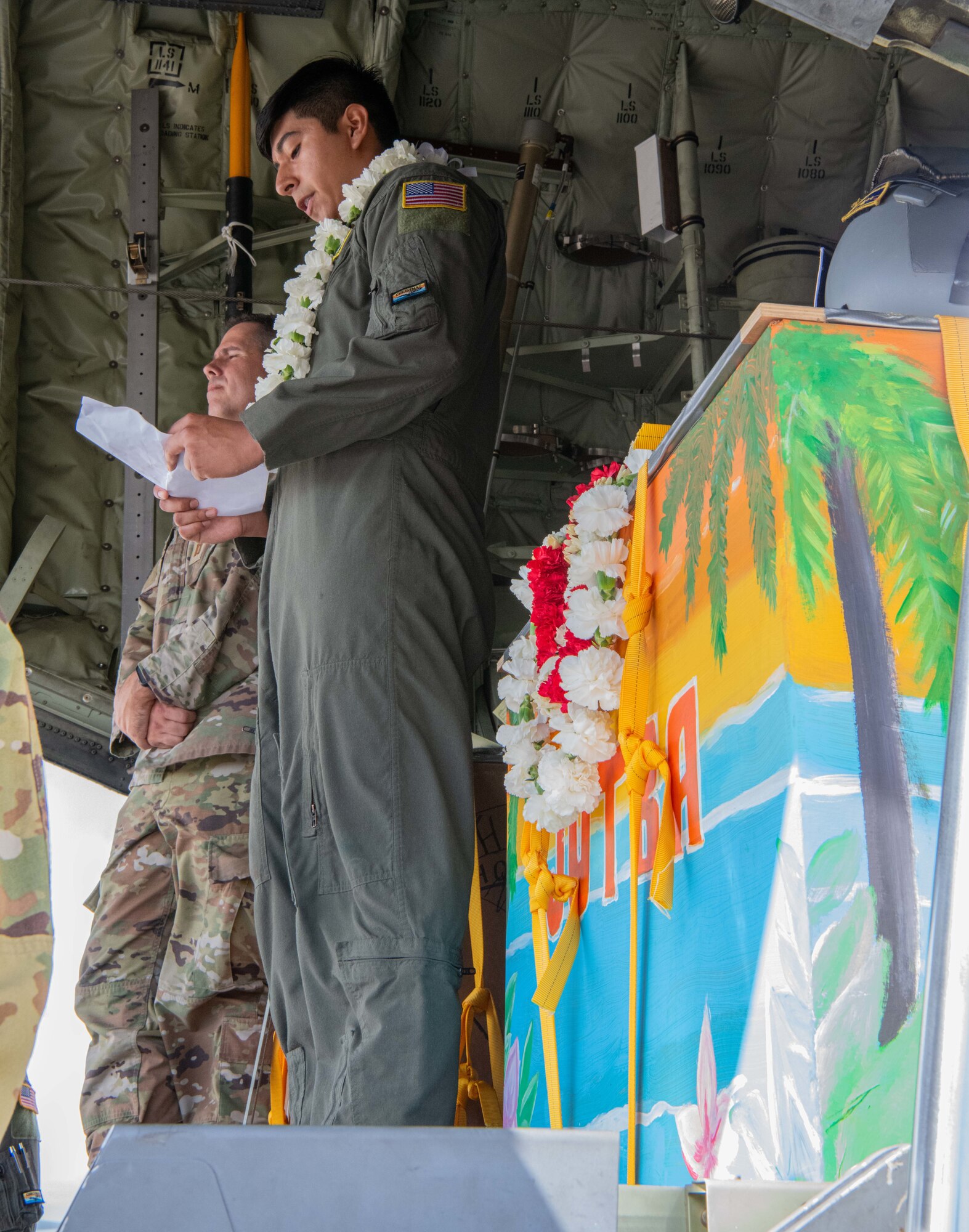 Airmen, family members, and international partners gathered at Andersen Air Force Base, Guam, December 12, 2024, to honor U.S. Air Force Senior Airman Jeremy Jutba-Hake, who passed away in 2015 while supporting Operation Christmas Drop. A commemorative aid bundle signed by attendees was later delivered to remote Pacific islands as part of the annual humanitarian mission. (U.S. Air Force photo by [Photographer's Name])