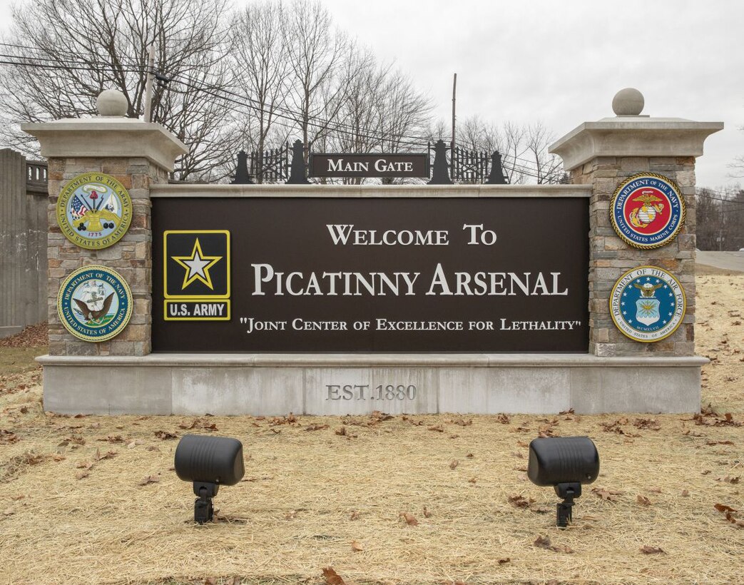 A large sign, with stone columns on each side, reads "Welcome to Picatinny Arsenal."