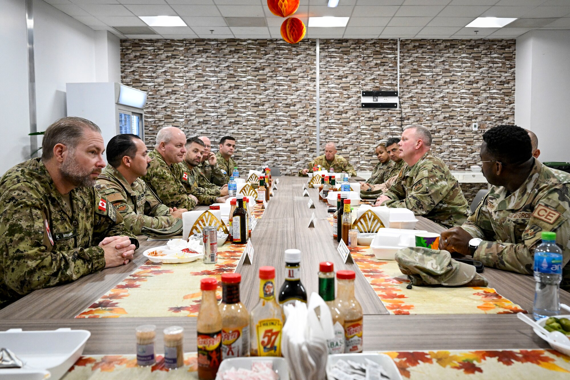 Canadian Armed Forces military members and U.S. Air Force military members talk while sitting at a table.