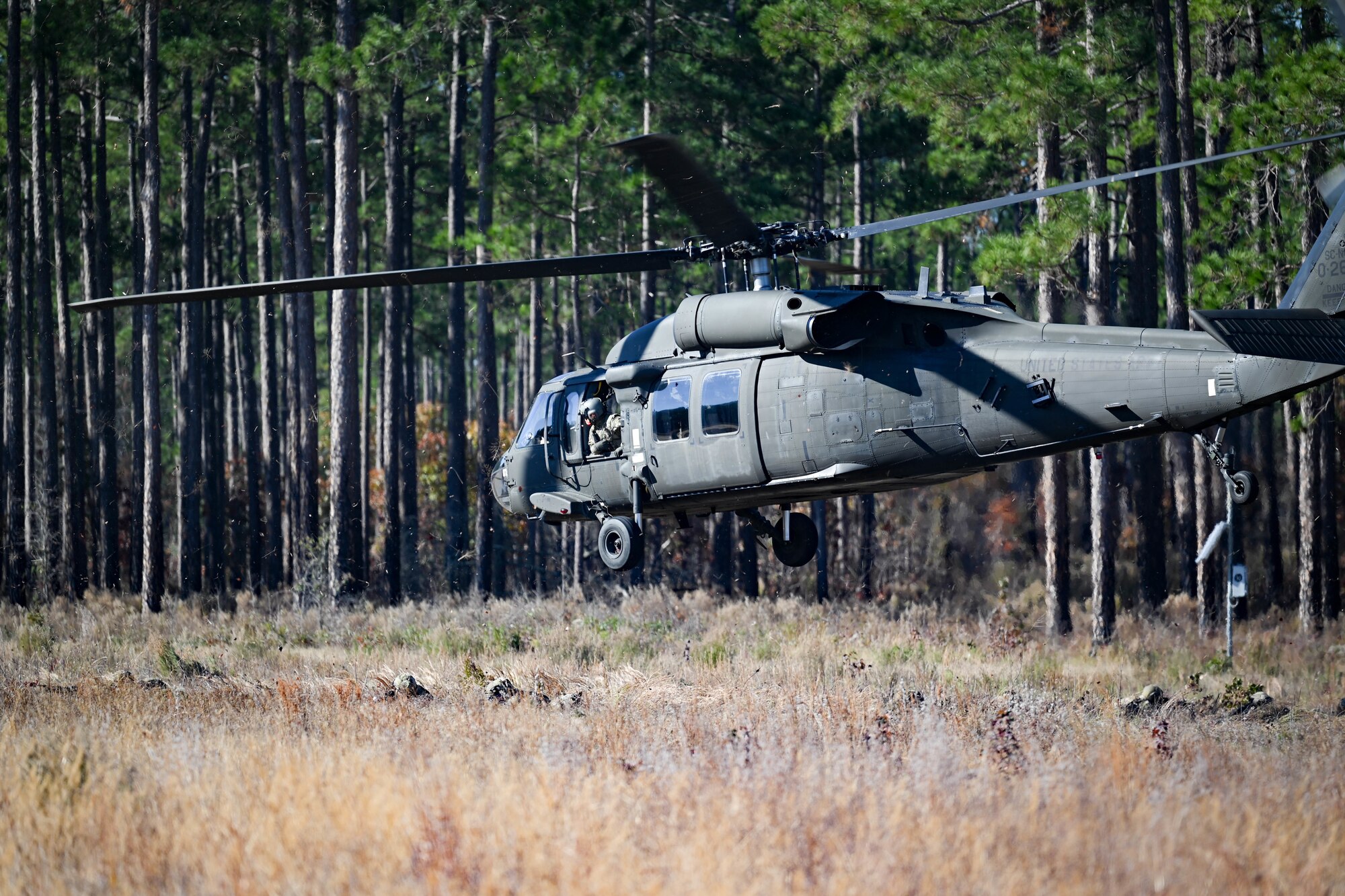 A UH-60 Black Hawk drops off Airmen in a field.
