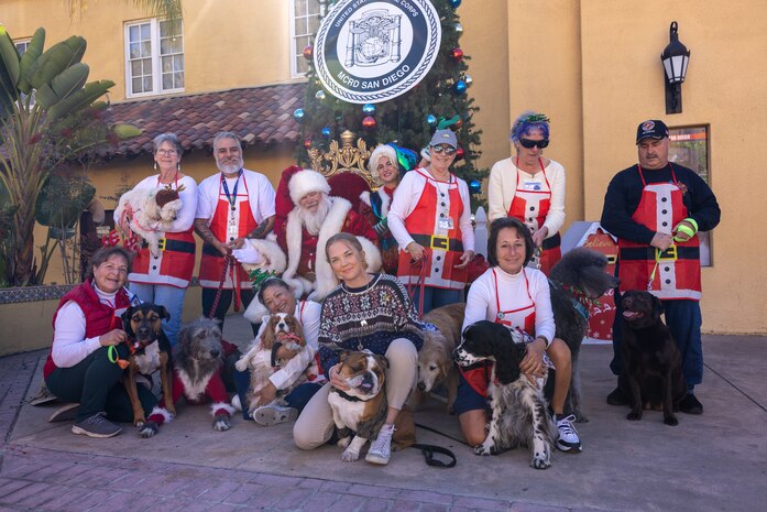 U.S. Marine Corps Cpl. Sarah Grawcock, a combat photographer and the mascot handler, and Lance Cpl. Bruno, the Marine Corps Recruit Depot San Diego and the Western Recruiting Region mascot, pose with dogs and volunteers from Independent Therapy Dogs Incorporated at the Holiday Express event at Marine Corps Recruit Depot San Diego, California, Dec. 7, 2024. The Holiday Express is an annual event held at the Depot to bring holiday cheer to Marines, civilian employees and their families with crafts, music, opportunity drawings and more. (U.S. Marine Corps photo by Cpl. Alexander O. Devereux)