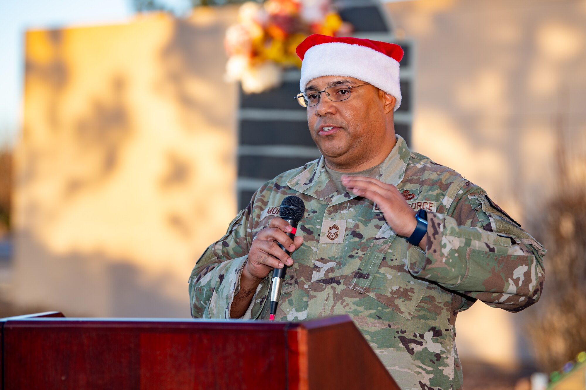 Chief MSgt. Gerald Morey is holding a microphone while standing behind a podium.