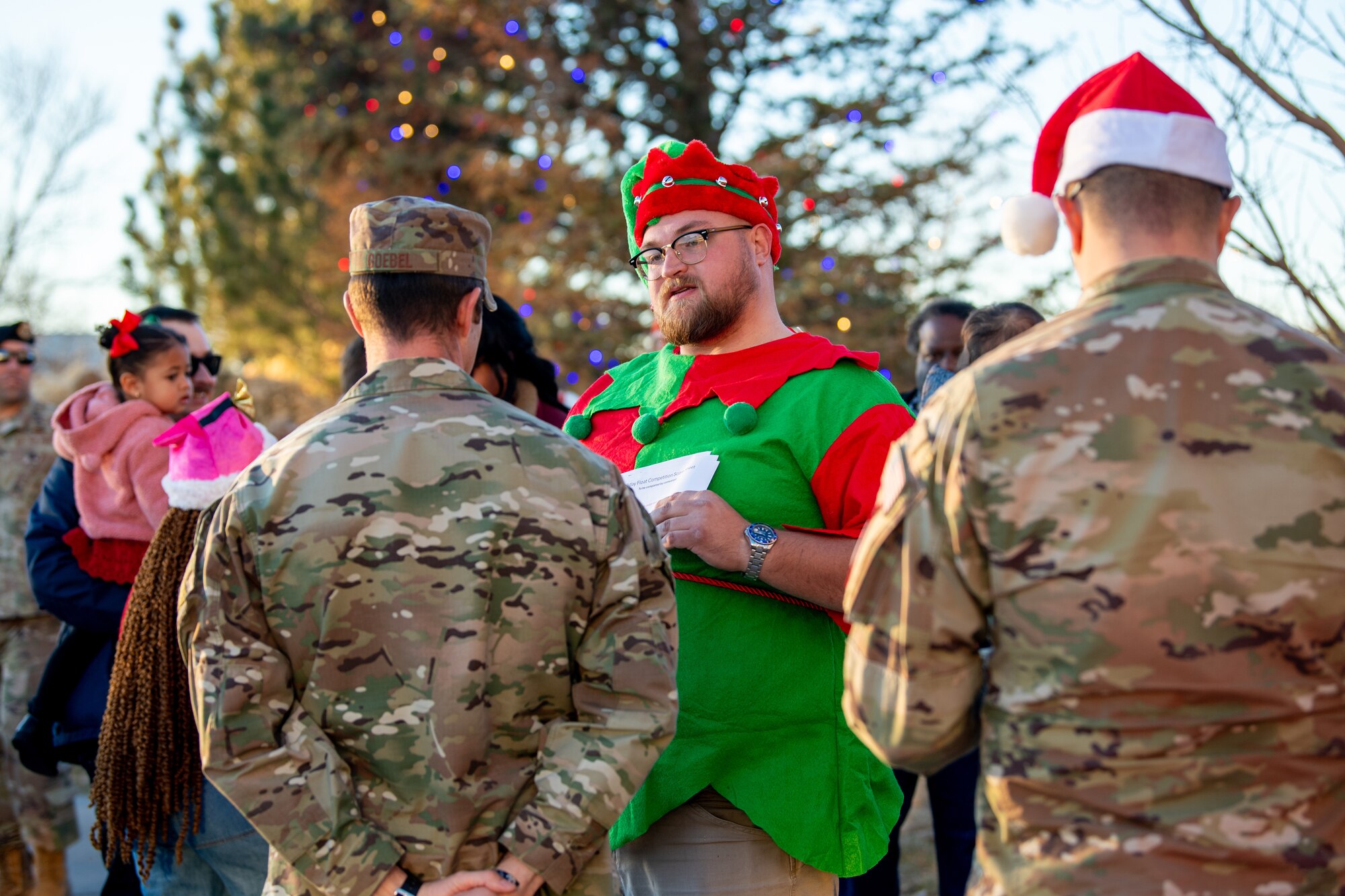 A member dressed up as Santa's helper talks with service members.