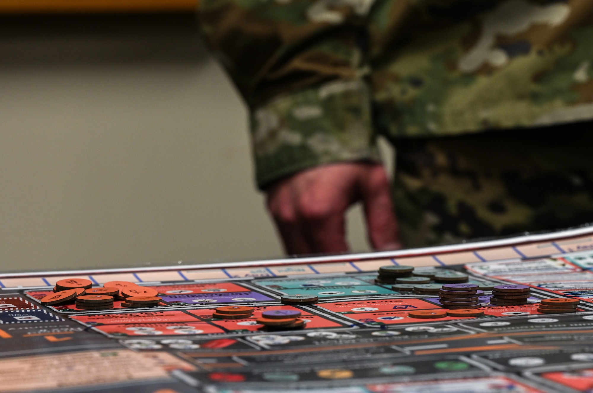 Several uniformed servicemembers huddle, roll dice and move small disks to advance a war board game called Kingfish ACE.