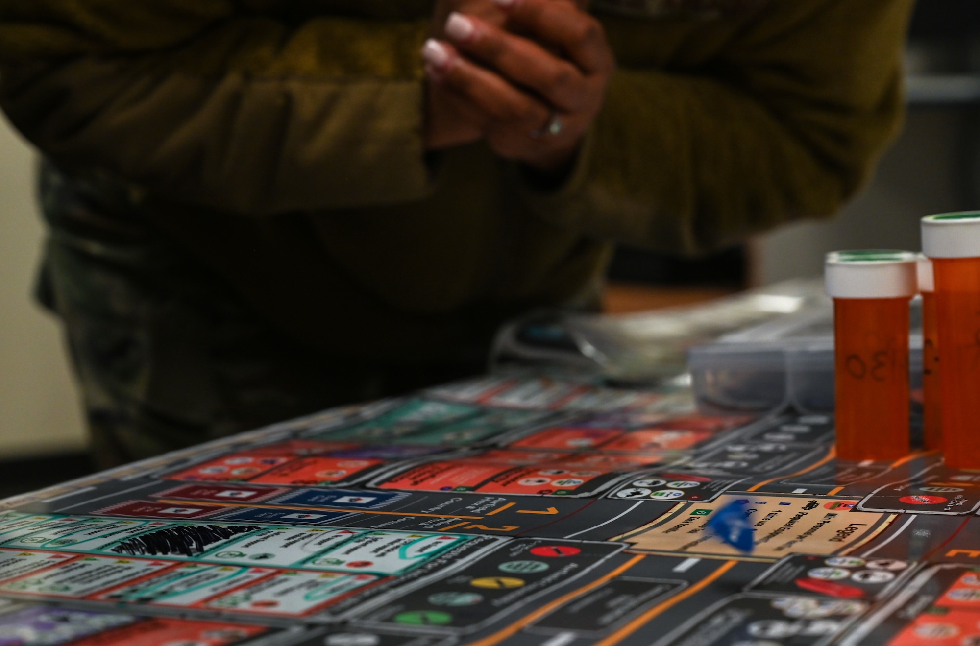 Several uniformed servicemembers huddle, roll dice and move small disks to advance a war board game called Kingfish ACE.