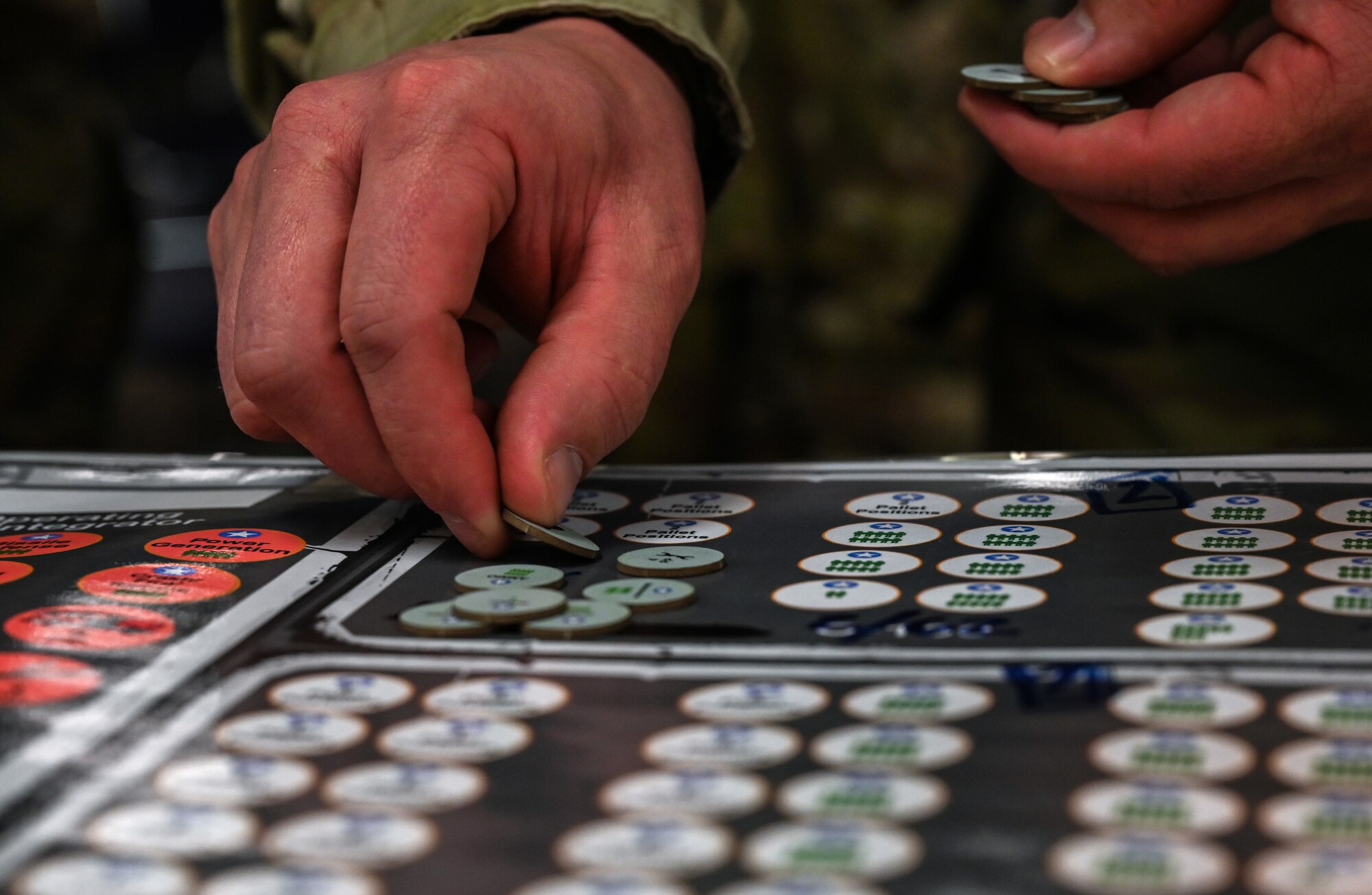Several uniformed servicemembers huddle, roll dice and move small disks to advance a war board game called Kingfish ACE.