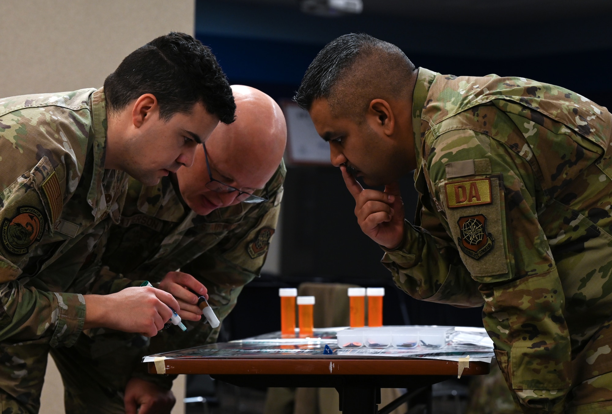 Several uniformed servicemembers huddle, roll dice and move small disks to advance a war board game called Kingfish ACE.