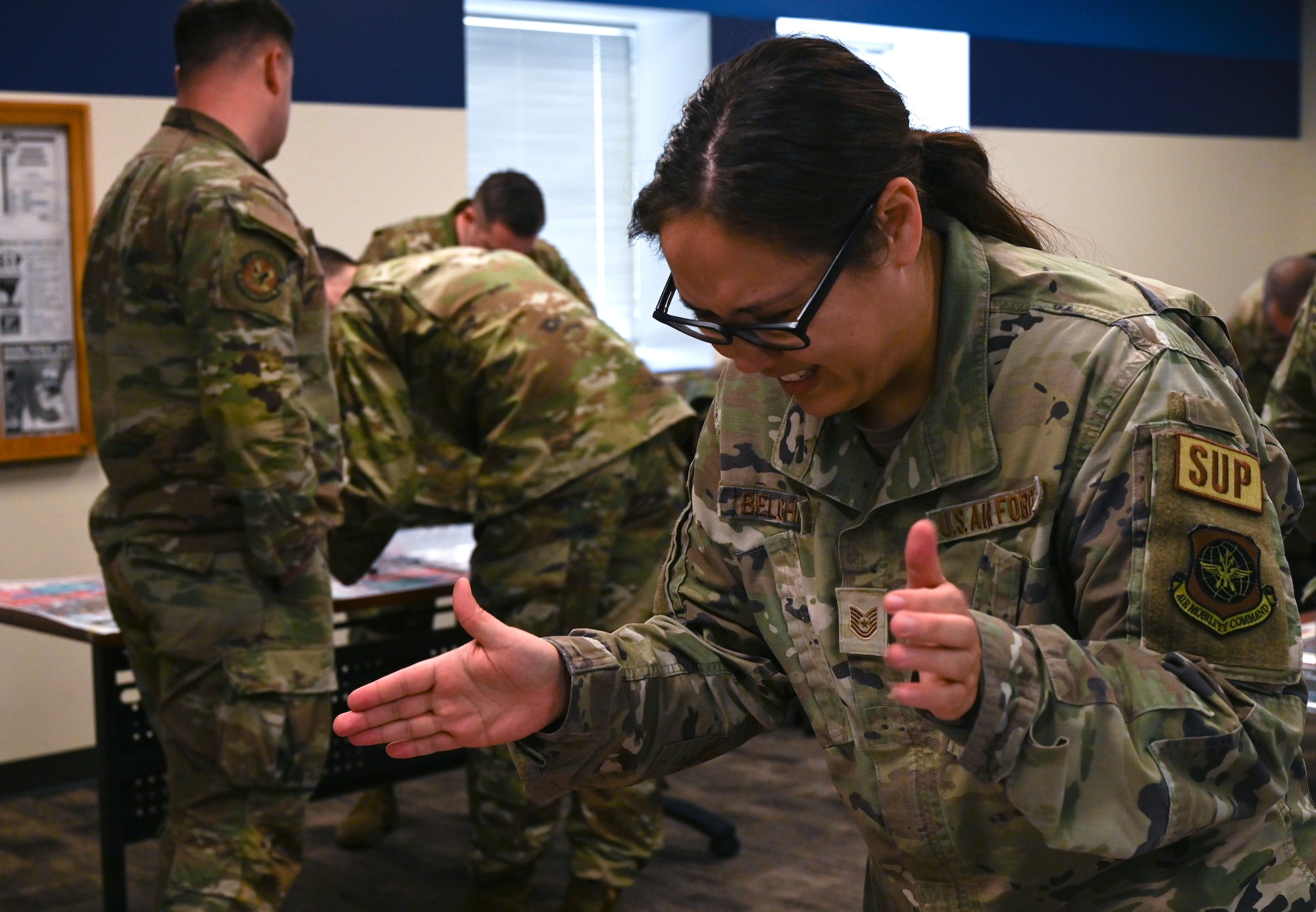 Several uniformed servicemembers huddle, roll dice and move small disks to advance a war board game called Kingfish ACE.