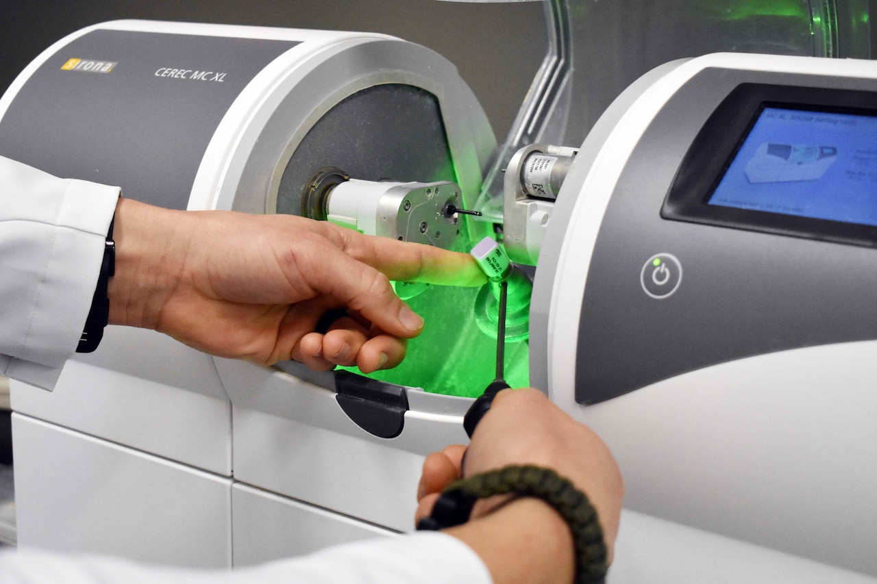 Hands touch a piece of equipment that glows green.