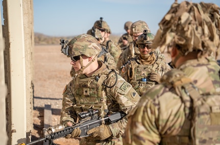 Spc. Jack Clark, 1st Battalion, 186th Infantry Regiment, Oregon Army National Guard, moves through a wall opening while Staff Sgt. Arturo Veloz supervises during urban operations training at Camp McGregor, New Mexico, Dec. 15, 2024. The unit is preparing to deploy to the Multinational Force and Observers mission in Egypt's Sinai Peninsula.