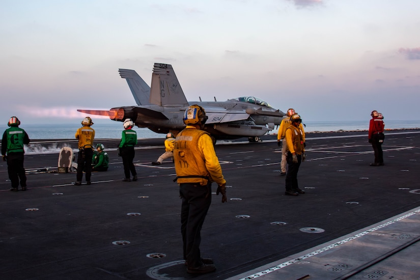 Sailors direct an aircraft taking off from an aircraft carrier.