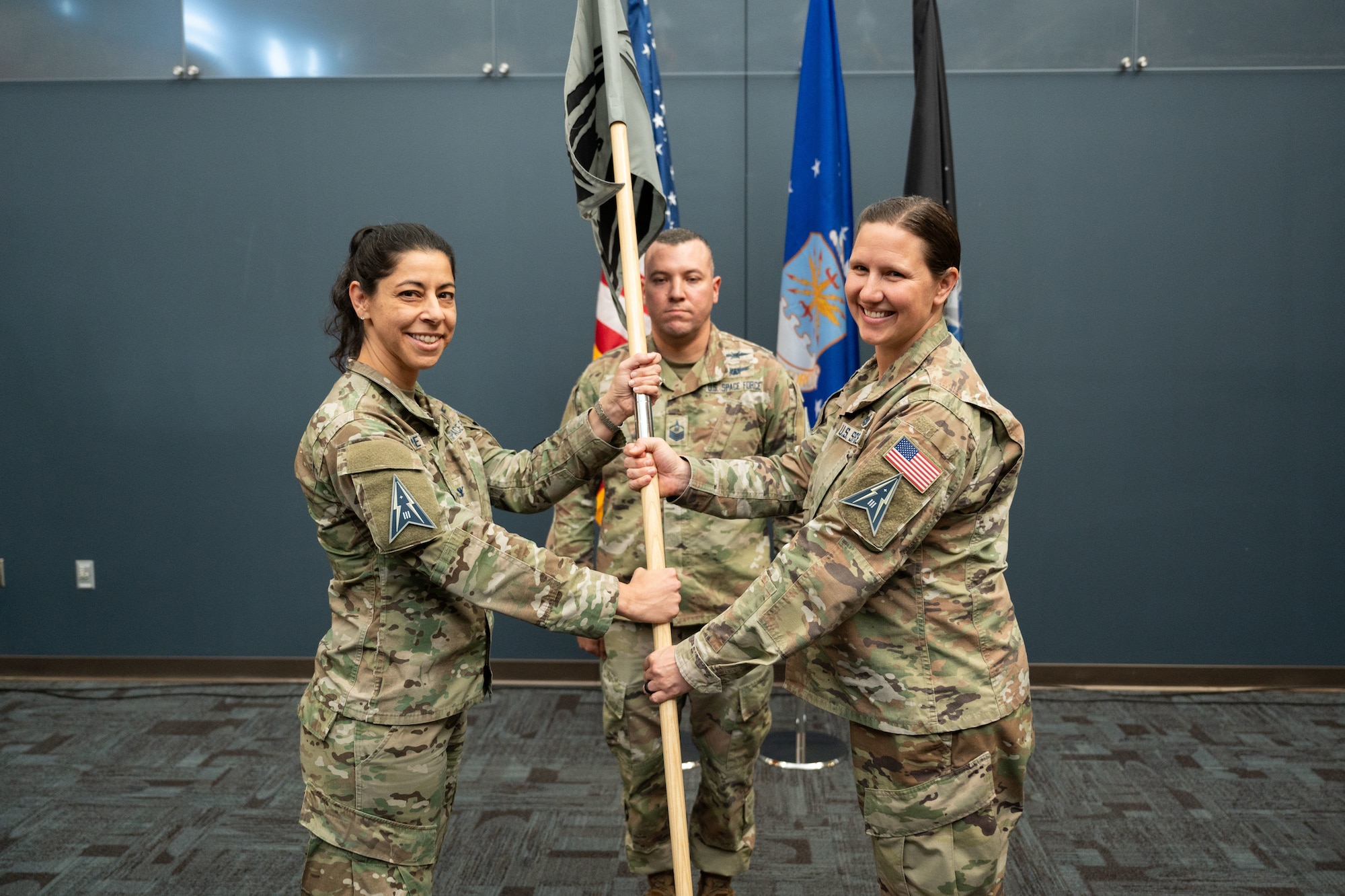 U.S. Space Force Lt. Col. Bridget Ajinga, 37th Tactical Intelligence Squadron commander and Col. Nicole Petrucci, Mission Delta 3 commander, pass the unit guidon as symbolic gesture during the 37th Tactical Intelligence Squadron activation ceremony, Nov. 15, 2024 at Peterson Space Force Base, Colorado. The 37th TIS, which aligns under Mission Delta 3 – Electromagnetic Warfare, is the first intelligence squadron under the mission delta construct that integrates intelligence, cyber, and sustainment within mission deltas.