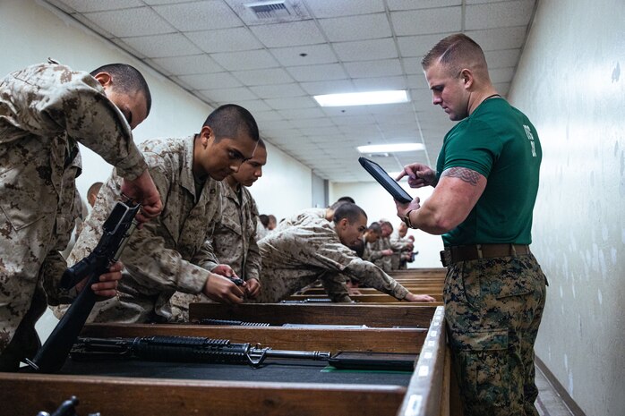 U.S. Marine Corps Sgt. Tristan Taylor, a drill instructor with Support Battalion, Recruit Training Regiment, inspects a recruits M16-A4 service rifle during a practical application exam at Marine Corps Recruit Depot San Diego, California, Dec. 11, 2024. Following the knowledge exam, now taken on tablets in an effort to modernize the Marine Corps, recruits are evaluated on tactical combat casualty care, and how to disassemble and reassemble their M16A4 service rifles as taught throughout the duration of recruit training. Recruits have several opportunities to practice before exam one and the practical application test. (U.S. Marine Corps photo by Lance Cpl. Eric Valerio)