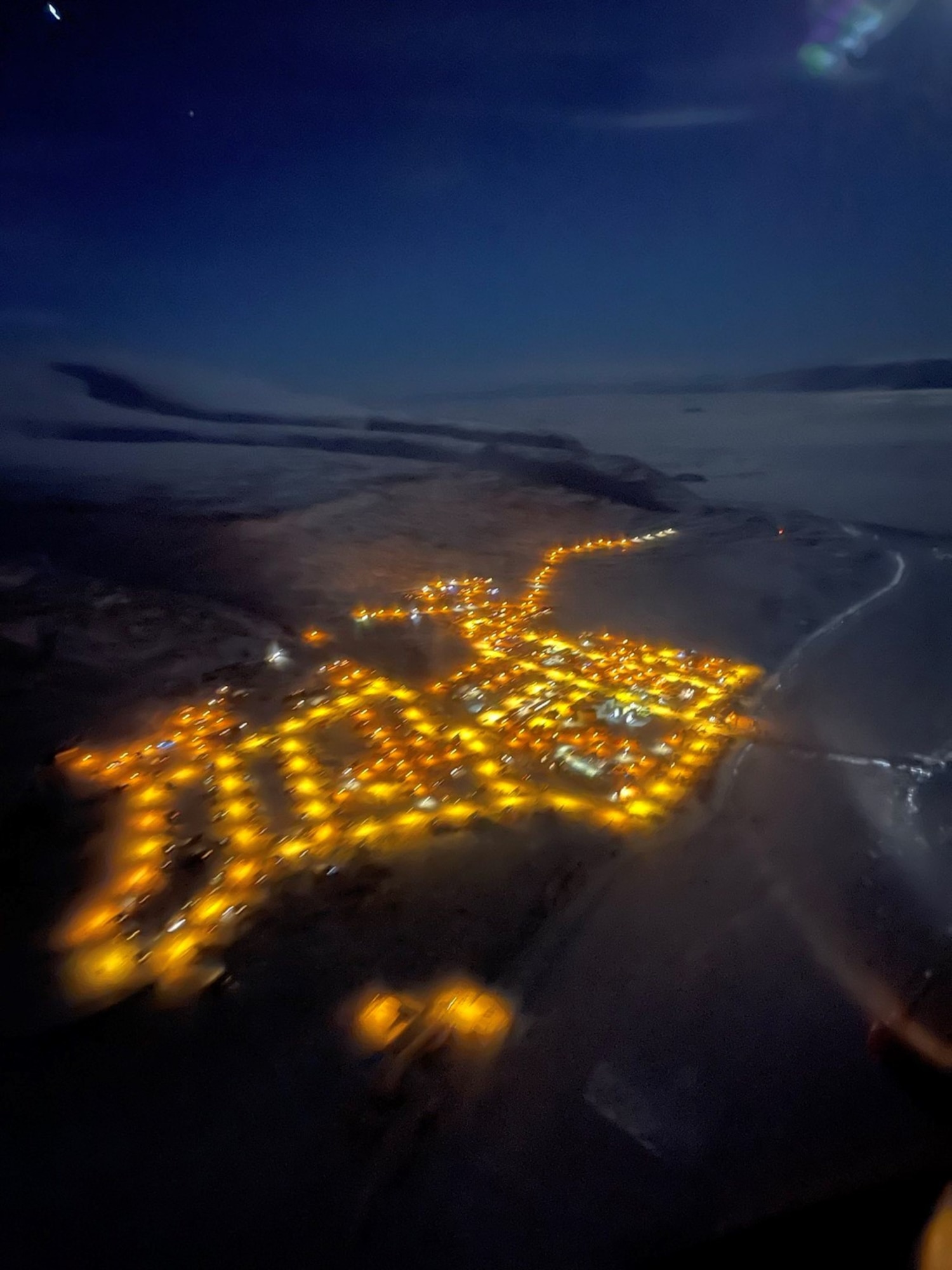 Aerial photograph taken of Qaanaaq, Greenland at night with Christmas lights lighting up the sky.