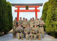 U.S. Army Soldiers assigned to the 382nd Military Police Detachment and 422nd Military Police Company, 96th Battalion, 11th Brigade, pose for a photo under the Sagami gate during Yama Sakura 87 at Sagami General Depot, Japan, Dec. 11, 2024.
