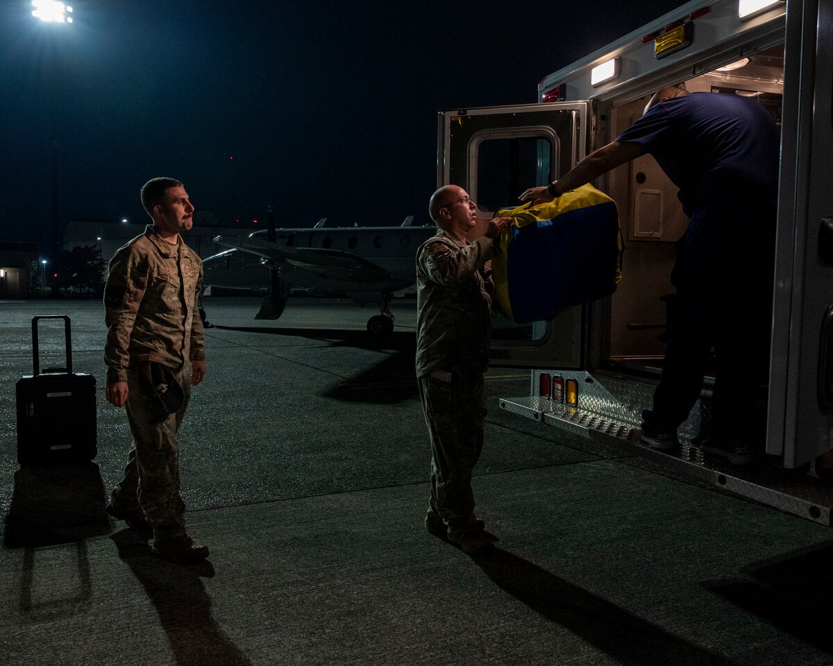 Military members load medical equipment onto an ambulance.