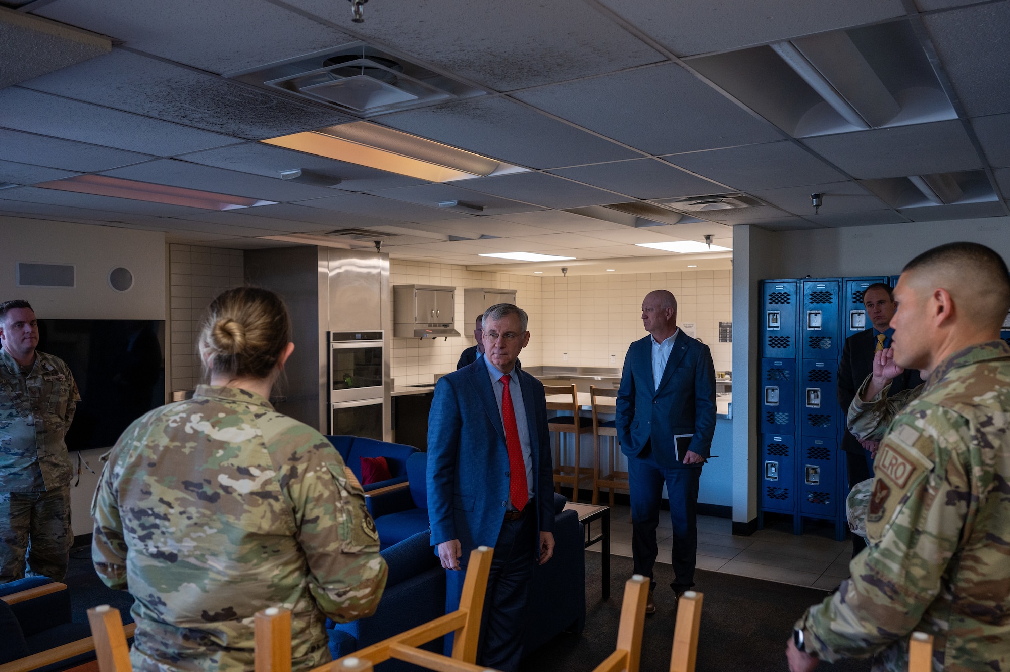 Men in suits and military members tour housing facilities