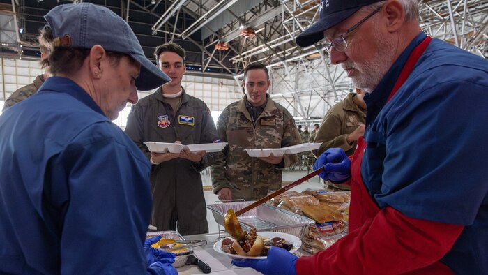 Military members watching BBQ being plated