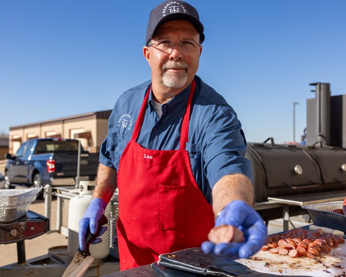 Man offering a piece of sausage to the camera