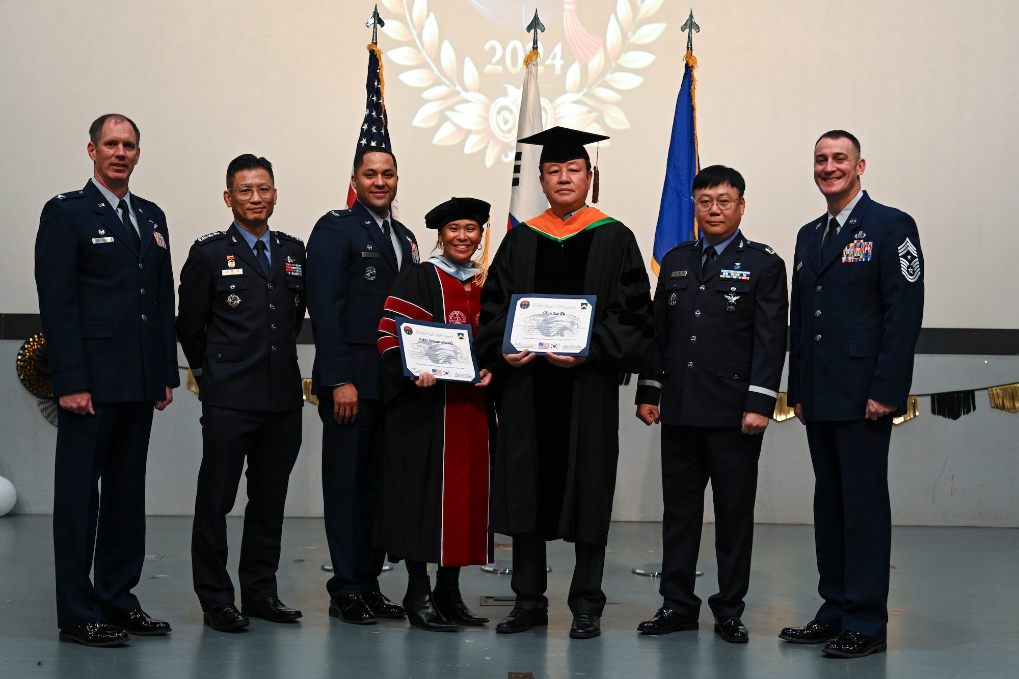 Doctoral degree recipients pose with base leadership during the Joint Force Graduation ceremony at Kunsan Air Base, Republic of Korea.