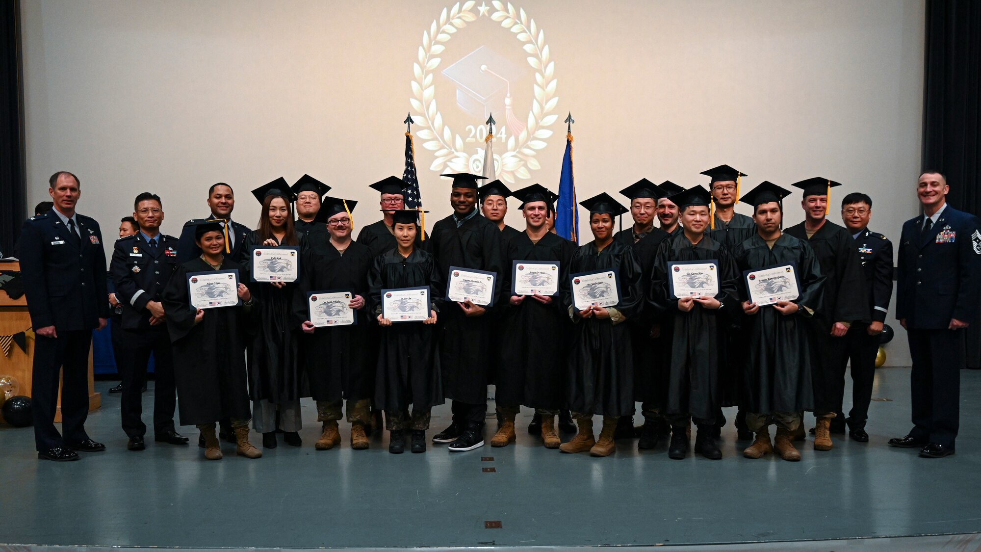 Master’s degree recipients pose with base leadership during the Joint Force Graduation ceremony at Kunsan Air Base, Republic of Korea.
