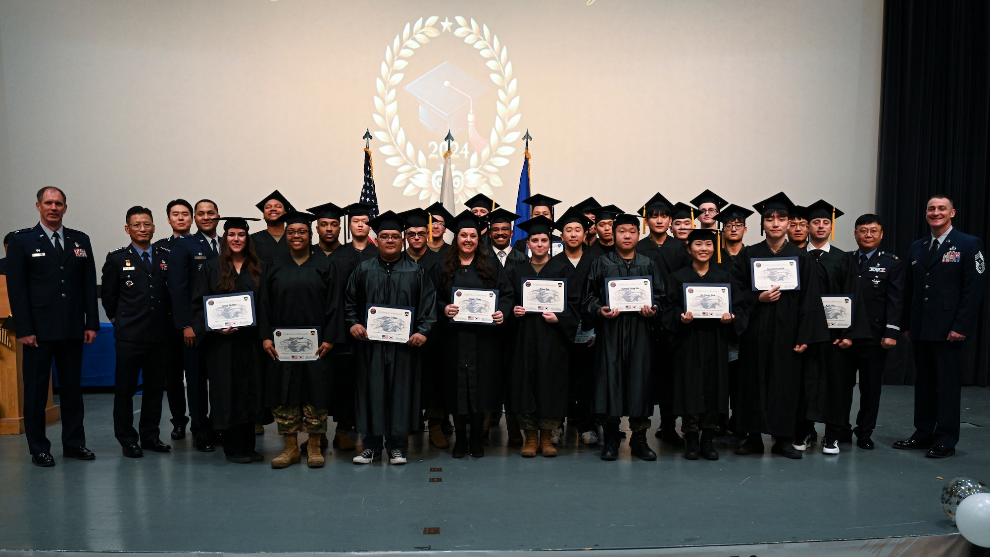 Bachelor’s degree recipients pose with base leadership during the Joint Force Graduation ceremony at Kunsan Air Base, Republic of Korea.