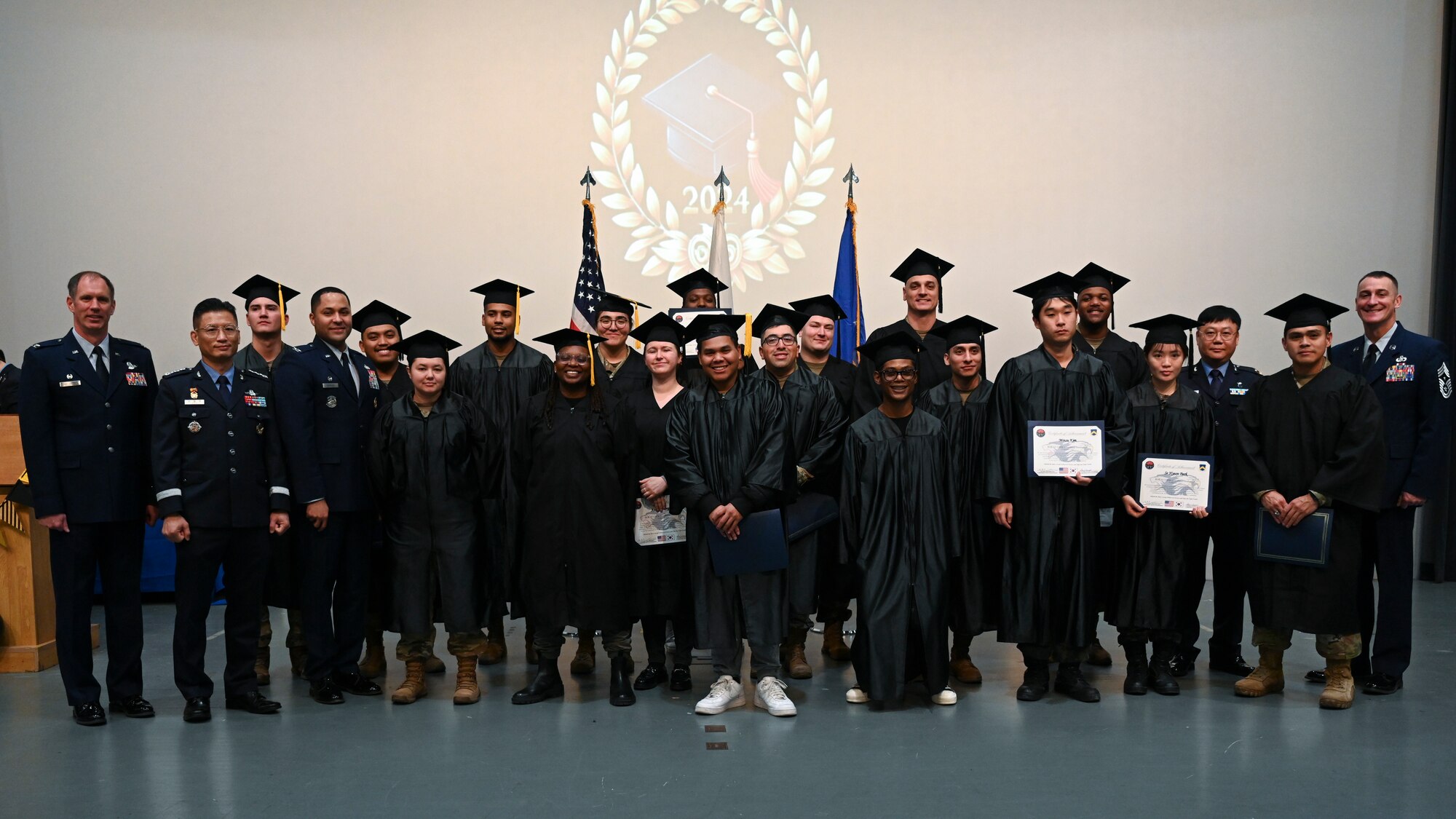 Associate degree recipients pose with base leadership during the Joint Force Graduation ceremony at Kunsan Air Base, Republic of Korea.