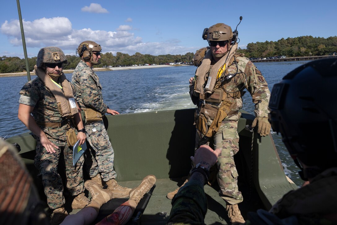 Three military members riding on a boat transporting a simulated casualty.