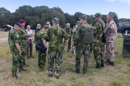 Military members from allied nations talking in a circle.