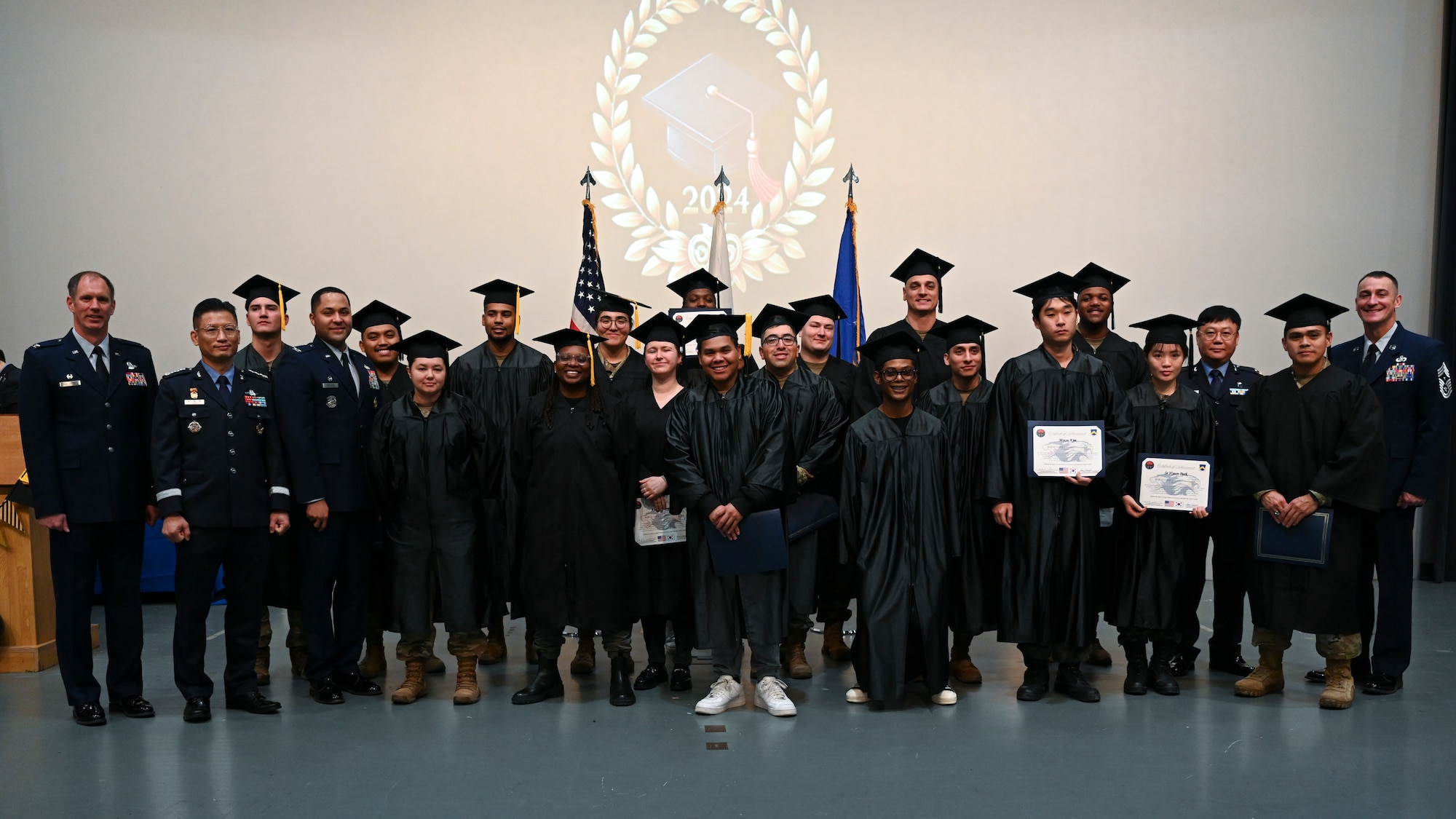 Associate degree recipients pose with base leadership during the Joint Force Graduation ceremony at Kunsan Air Base, Republic of Korea.