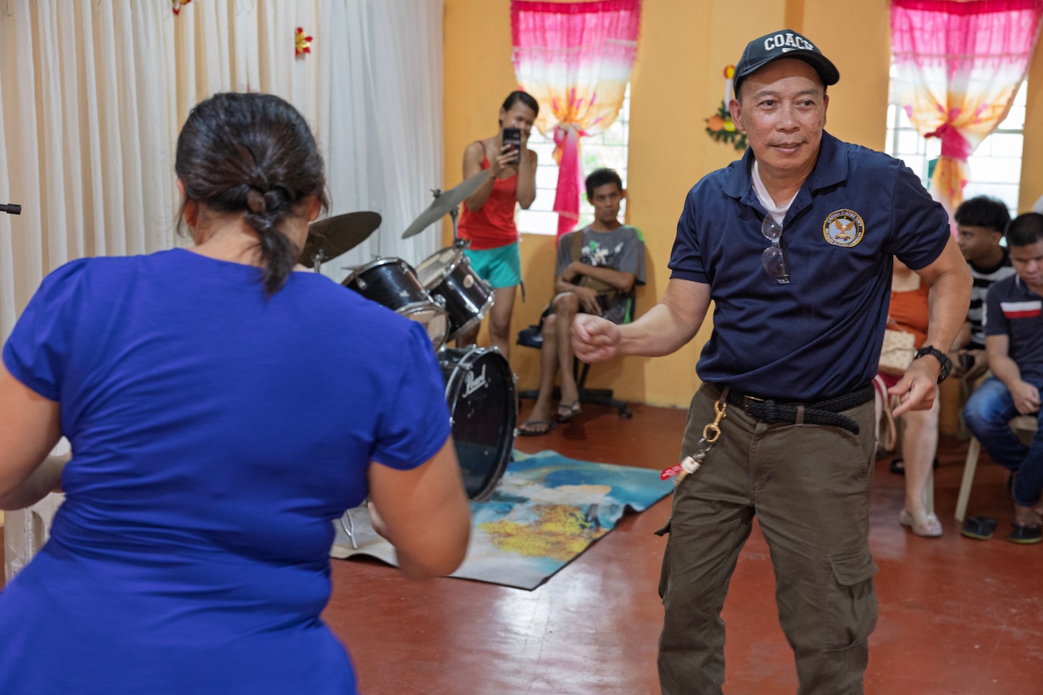 Civilian mariner Larry P. Ejan, steward utilityman, with Military Sealift Command’s (MSC) dry cargo and ammunition ship USNS Charles Drew (T-AKE 10), dances with a staff member of the Niños Pag Asa Orphanage Center, during a community outreach event in Olongapo, Philippines, Dec. 8, 2024.