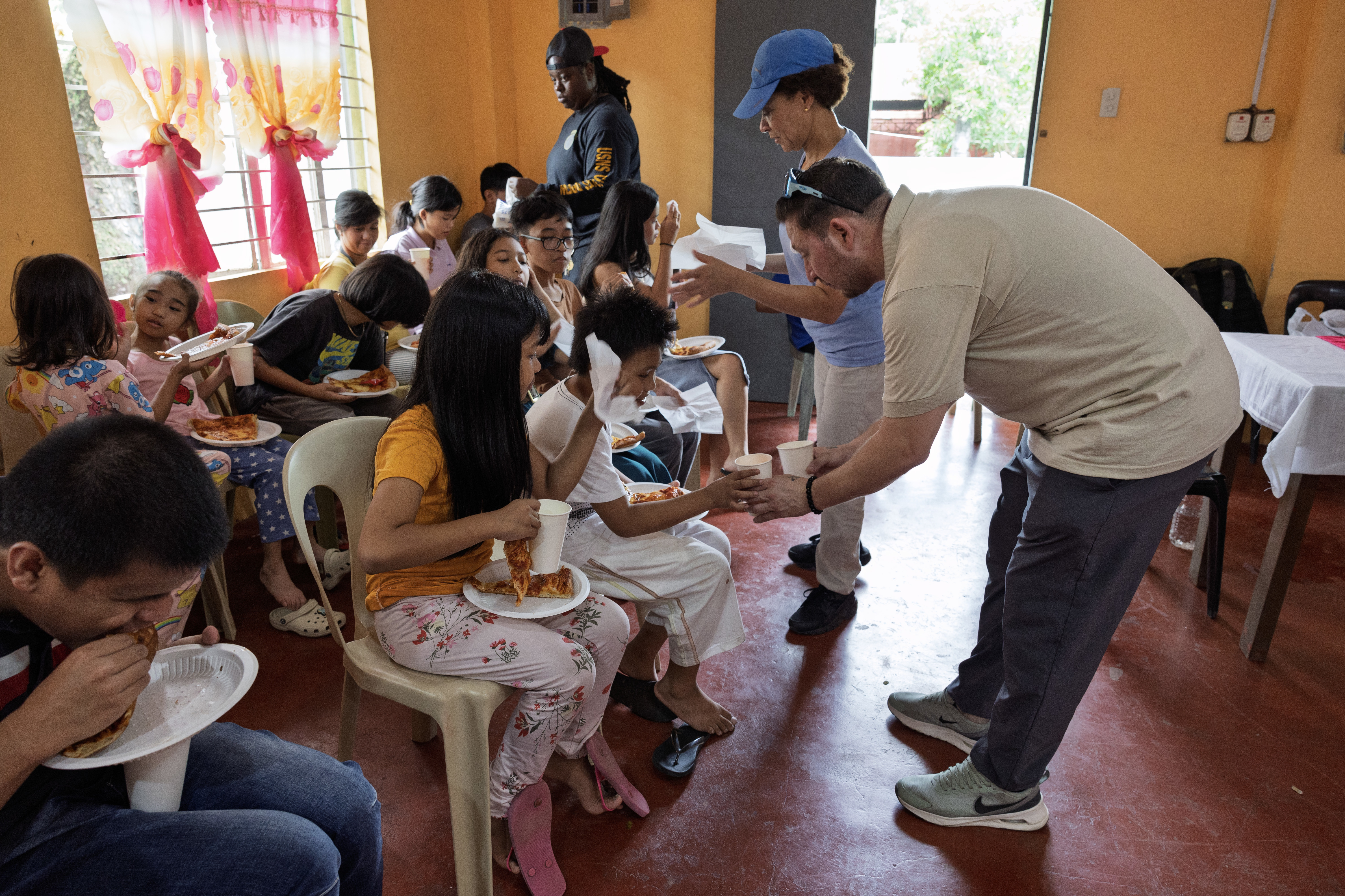 Volunteers with Military Sealift Command’s dry cargo and ammunition ship USNS Charles Drew (T-AKE 10), hand out food to children of the Niños Pag Asa Orphanage Center, during a community outreach event in Olongapo, Philippines, Dec. 8, 2024.