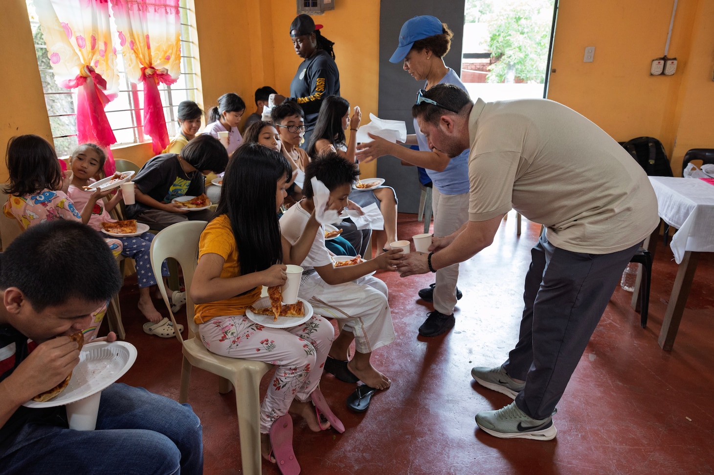 Volunteers with Military Sealift Command’s dry cargo and ammunition ship USNS Charles Drew (T-AKE 10), hand out food to children of the Niños Pag Asa Orphanage Center, during a community outreach event in Olongapo, Philippines, Dec. 8, 2024.