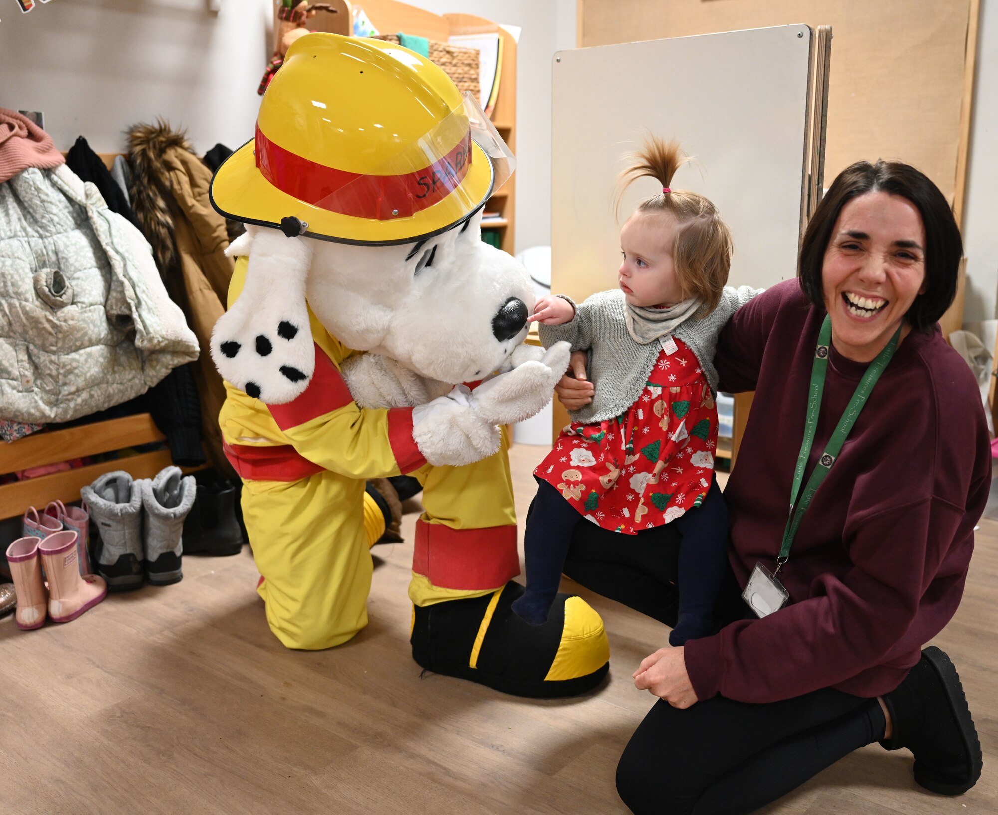 Sparky the Fire Dog from the 100th Air Refueling Wing, Royal Air Force Mildenhall, visits children at Little Treasures Pre-School and gives out hugs and high-fives in Mildenhall, England, Dec. 13, 2024. The 100th Civil Engineer Squadron Fire Department mascot also stopped by to say hello to members of the local Suffolk Constabulary at the nearby police station while he was out and about in the local community. (U.S. Air Force photo by Karen Abeyasekere)