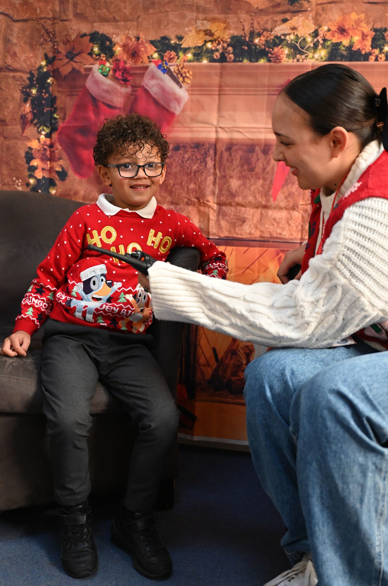 U.S. Air Force Staff Sgt. Isobelle Leftridge, 100th Communications Squadron commander’s support staff technician, uses a hand-held radio to encourage a Reception-Year child to interact with Santa at Beck Row Primary Academy, Beck Row, England, Dec. 12, 2024. A team of eight Airmen and civilians from Royal Air Force Mildenhall spent time with 81 children and provided them a chance to talk to Santa and make special gift requests before the holidays. (U.S. Air Force photo by Karen Abeyasekere)