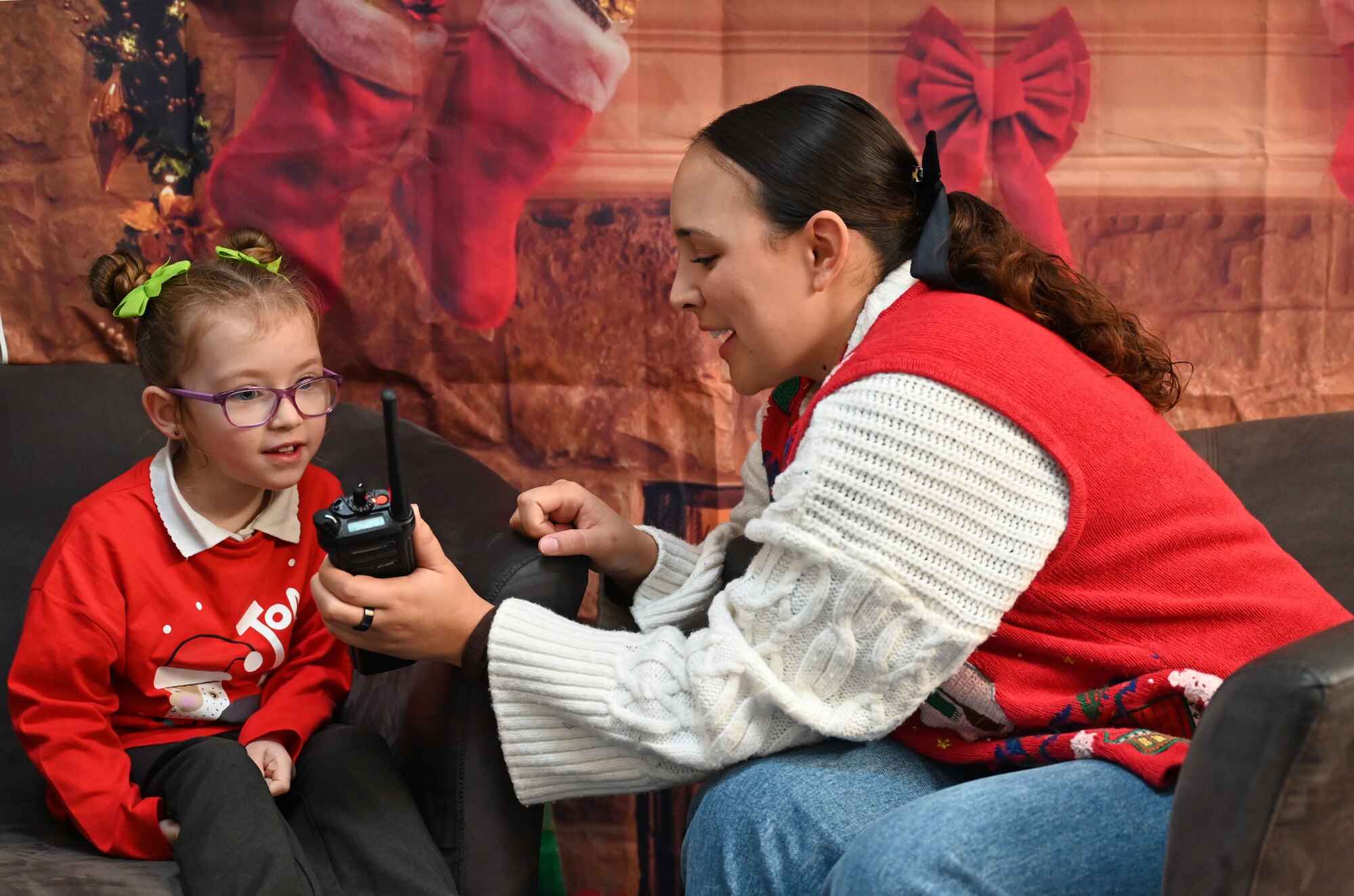 U.S. Air Force Staff Sgt. Isobelle Leftridge, 100th Communications Squadron commander’s support staff technician, uses a hand-held radio to encourage a Year-1 child to interact with Santa at Beck Row Primary Academy, Beck Row, England, Dec. 12, 2024. A team of eight Airmen and civilians from Royal Air Force Mildenhall spent time with 81 children and provided them a chance to talk to Santa and make special gift requests before the holidays. (U.S. Air Force photo by Karen Abeyasekere)