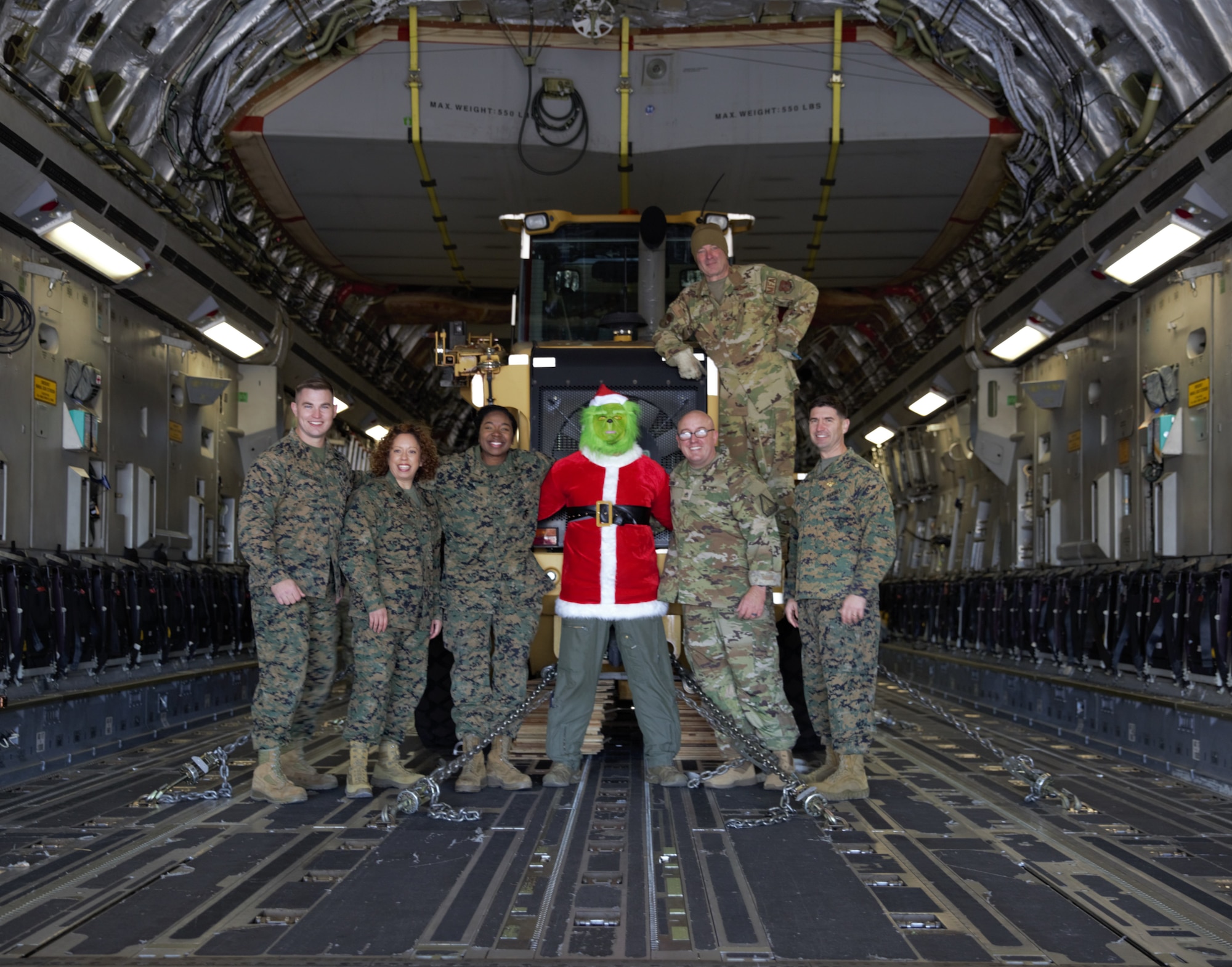 Service members and individual dressed as the Grinch pose for a photo after delivering presents.