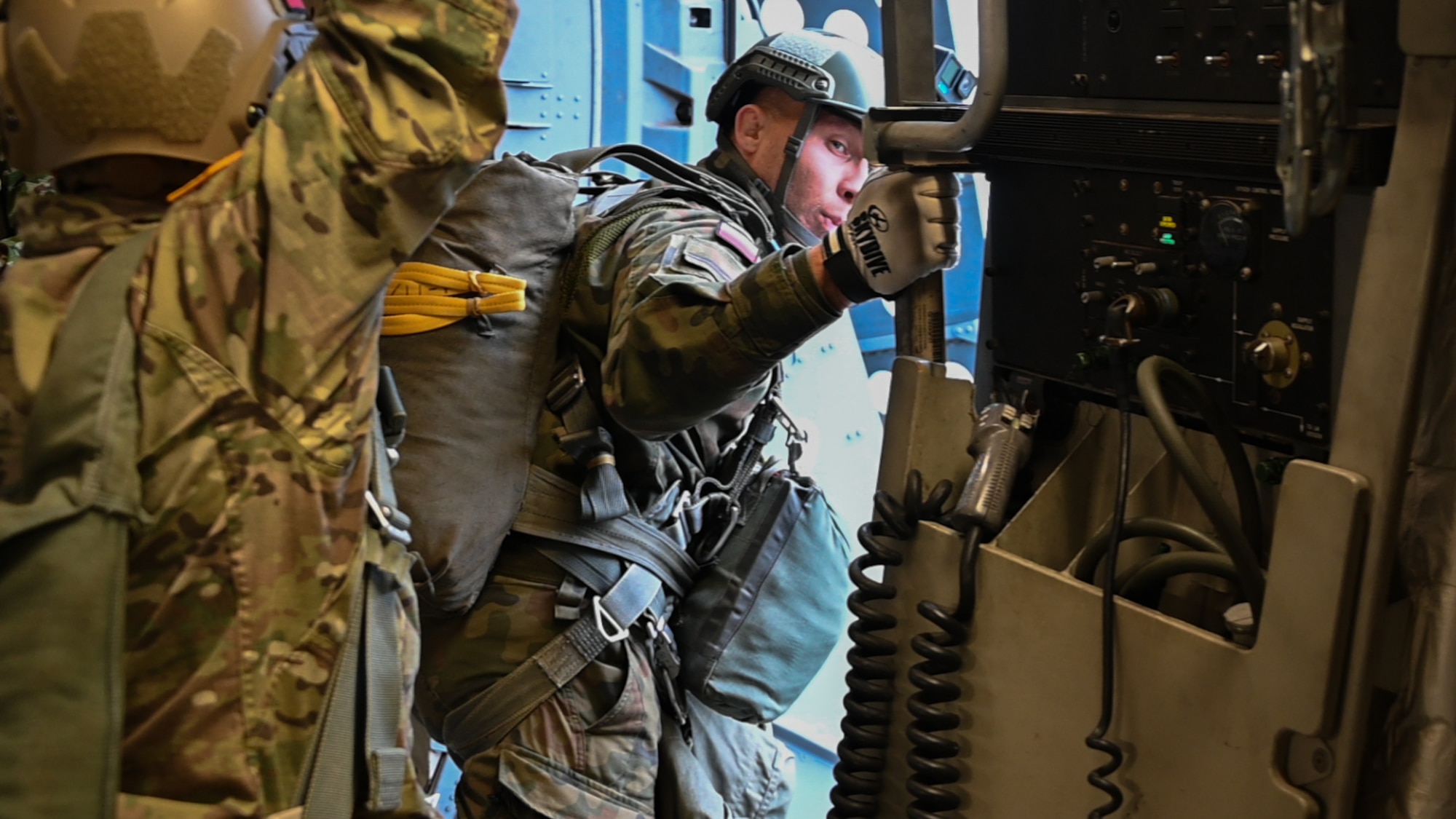 A Polish Armed Forces jumpmaster inspects the door of a C-17 Globemaster III aircraft flying over Drop Zone Sicily at Fort Liberty, North Carolina, Dec. 9, 2024. The jumpmaster oversees the jump process, ensures safety through equipment checks, aircrew coordination, jump commands, and exit management. (U.S. Air Force photo by Senior Airman Kari Degraffenreed)