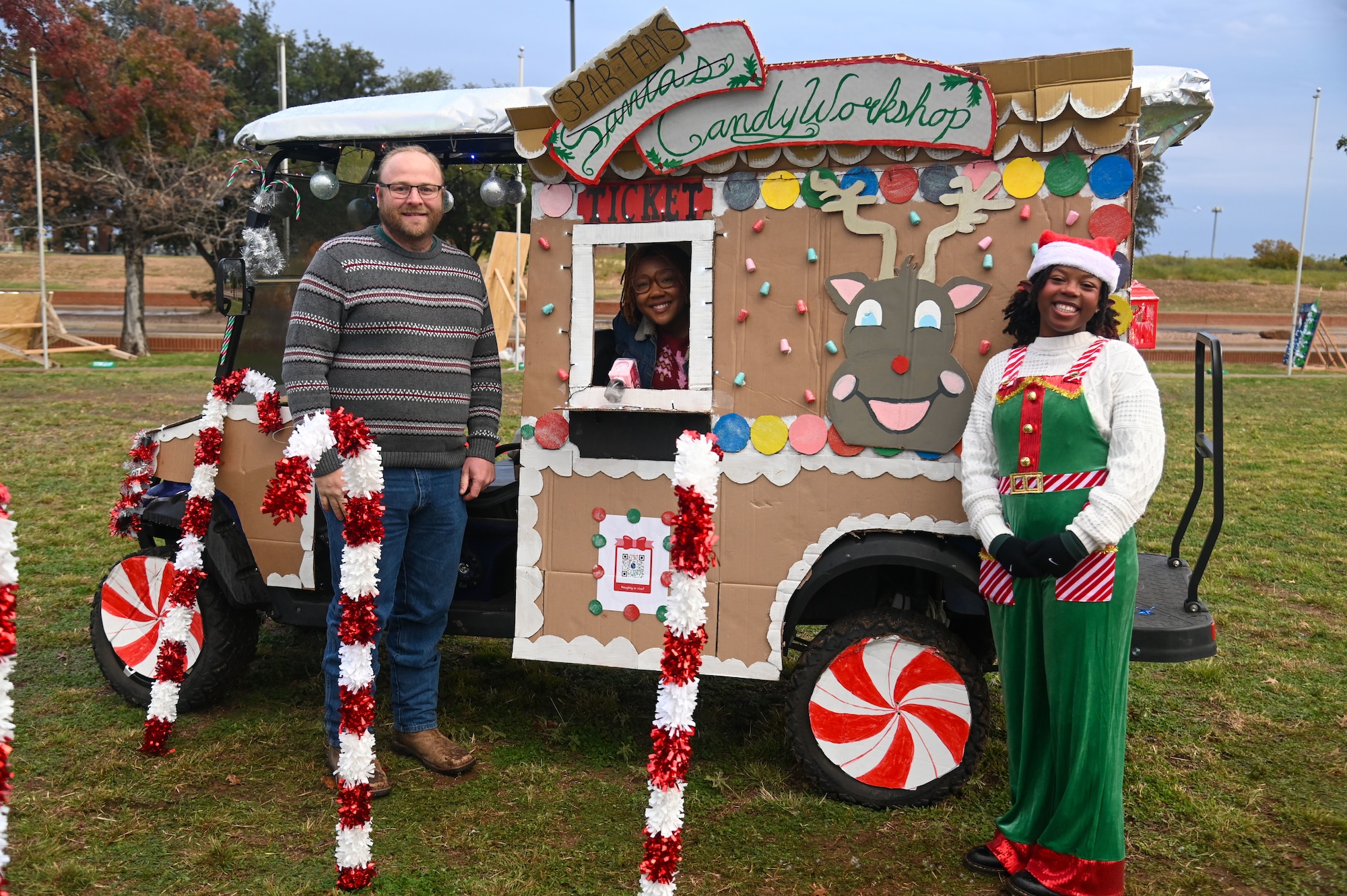 Members of the 17th Contracting Squadron pose in front of their decorated golf cart as part of the tree lighting ceremony at Goodfellow Air Force Base, Texas, Dec. 6, 2024. Various units across the base decorated their vehicles to participate in the Golf Cart Decorating contests. (U.S. Air Force photo by Airman 1st Class James Salellas)