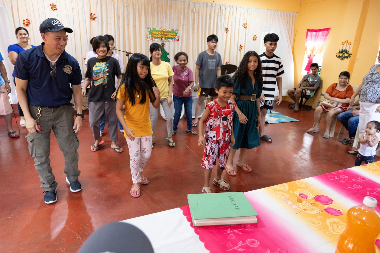 Civilian mariner Larry P. Ejan, left, steward utilityman, with Military Sealift Command’s (MSC) dry cargo and ammunition ship USNS Charles Drew (T-AKE 10), dances with children of the Niños Pag Asa Orphanage Center during a community outreach event in Olongapo, Philippines, Dec. 8, 2024.