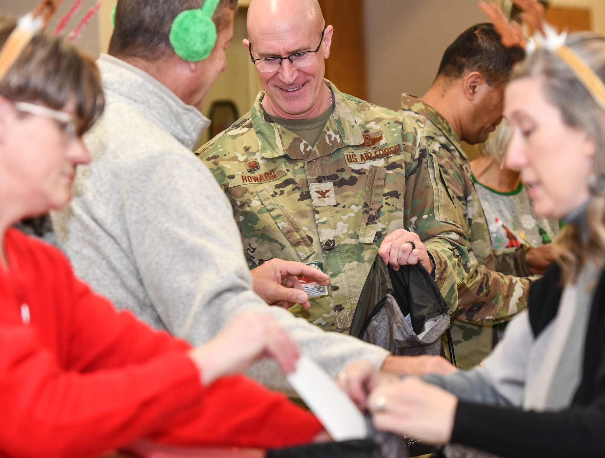 Col Mark Howard, 55th Wing commander, helps pack gift bags at the Bellevue Volunteer Fire Department on Dec. 11, 2024. Operation Holiday Cheer brought over 40 local community leaders and Offutt Airmen together to pack 480 gift bags for dormitory residents. (U.S. Air Force photo by Chad Watkins)