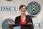 Cara Abercrombie stands behind a podium with DSCU banner behind her