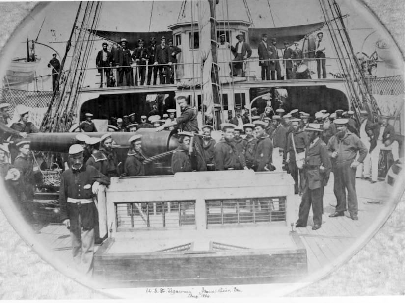 Several men stand on the deck of a ship for a photo.