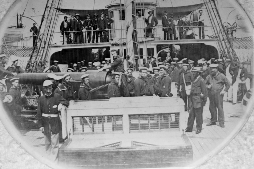 Several men stand on the deck of a ship for a photo.