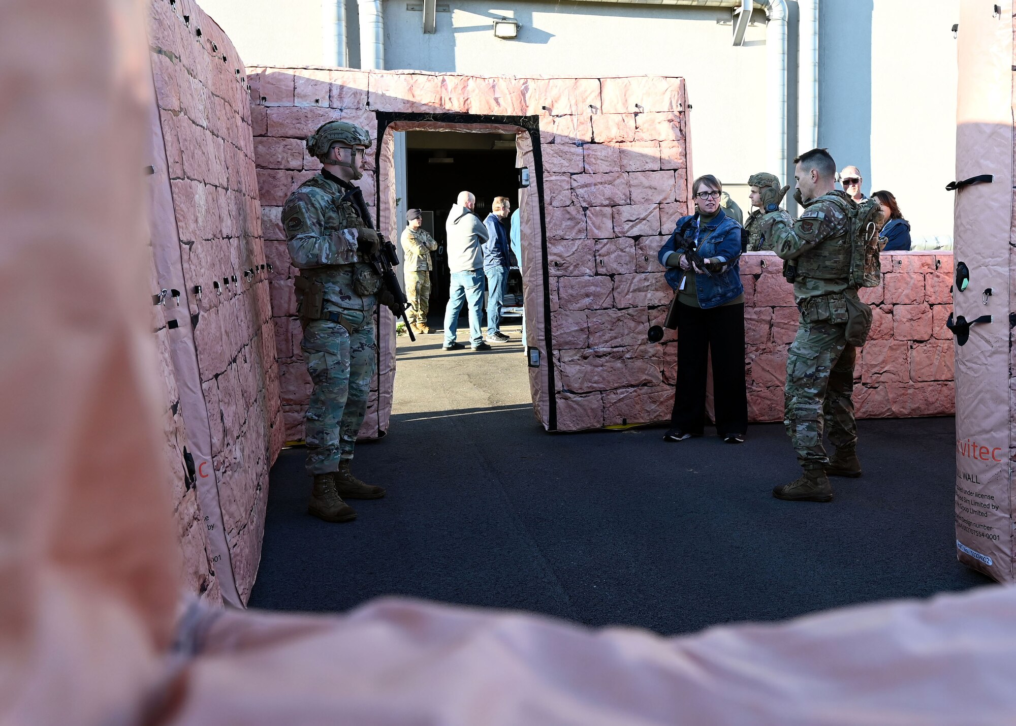 U.S. Air Force Tech. Sgt. Joel Ford, right, 445th Security Forces Squadron fire team leader, and Tech. Sgt. Jared Holliday, 445th SFS fire team leader, show Carla Caton, employer of U.S. Air Force Maj. Daniel Shields with the 445th Aeromedical Staging Squadron, how to maneuver inside a building simulating an urban environment during Employers Day at Wright-Patterson Air Force Base, Nov. 2, 2024. Civilian employees of Citizen Airmen were able to practice securing a building after being instructed by 445th SFS Airmen on proper maneuvers. (U.S. Air Force photo by Amanda Dick)