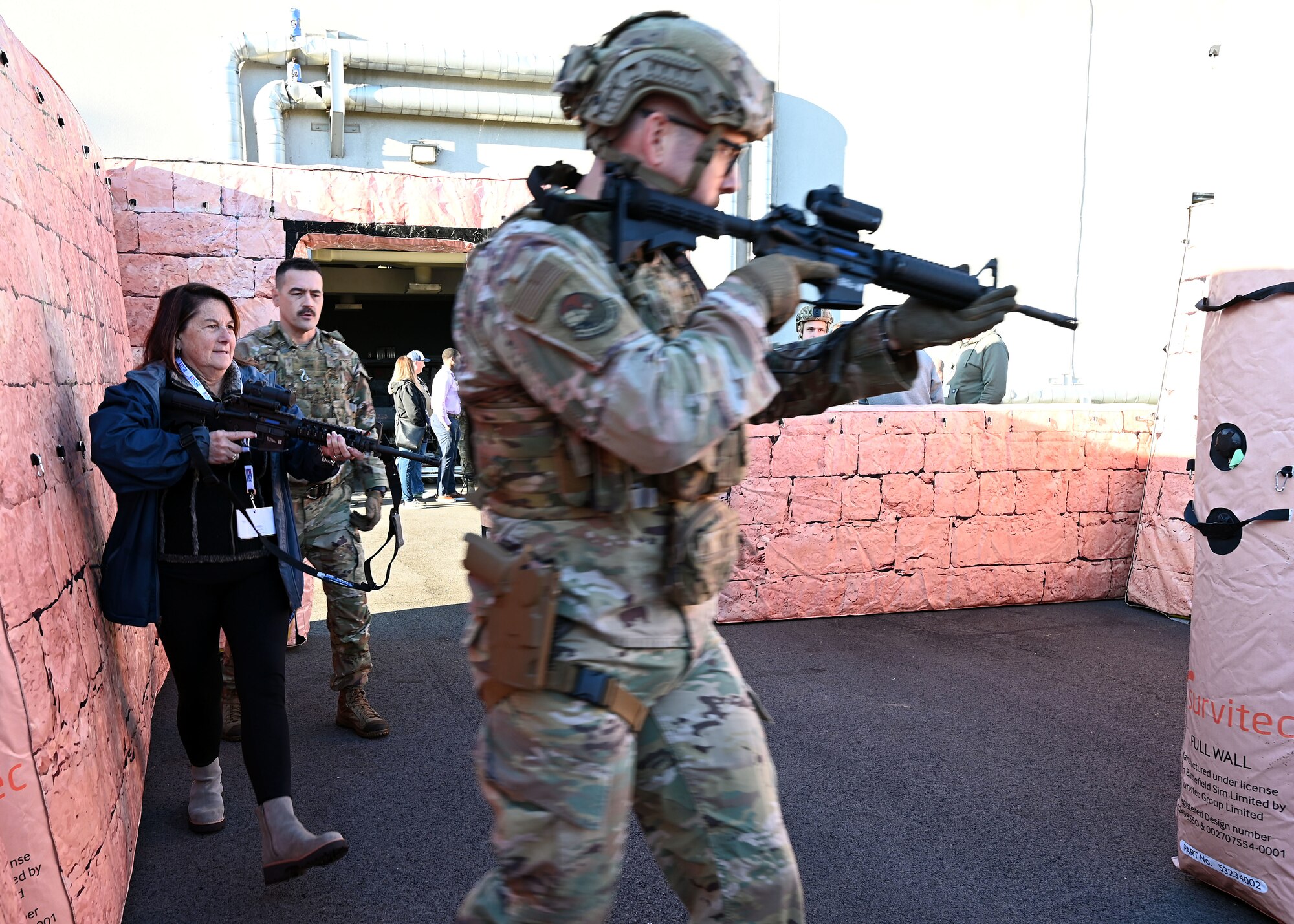 U.S. Air Force Tech. Sgt. Jared Holliday, front, 445th Security Forces Squadron fire team leader, and Karen Spaulding-Chicketti, employer of U.S. Air Force Master Sgt. Michelle Lee with the 445th Aeromedical Staging Squadron, secure a building in a simulated urban environment as Tech. Sgt. Joel Ford, 445th SFS fire team leader, provides instruction during Employers Day at Wright-Patterson Air Force Base, Nov. 2, 2024. Civilian employees of Citizen Airmen were able to practice securing a building after being instructed by 445th SFS Airmen on proper maneuvers. (U.S. Air Force photo by Amanda Dick)