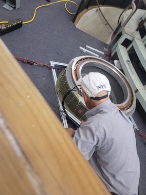 Shaun Andrew with Naval Air Warfare Center Training Systems Division (NAWCTSD) taps into the building power supply and hardwires the motor control unit to the fuse box.