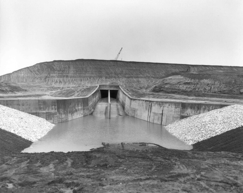 A view of the outlet works on the backside of the dam, during construction of the Lake O’ the Pines. The outlet works has two gates, which you can see in this photo that control the amount of water that is discharged from the lake. The discharge controls the level of the lake while providing proper flow to the river below the dam. The lake’s mission is to provide water to the Northeast Texas Municipal Water District and flood risk mitigation to communities along the Red River.